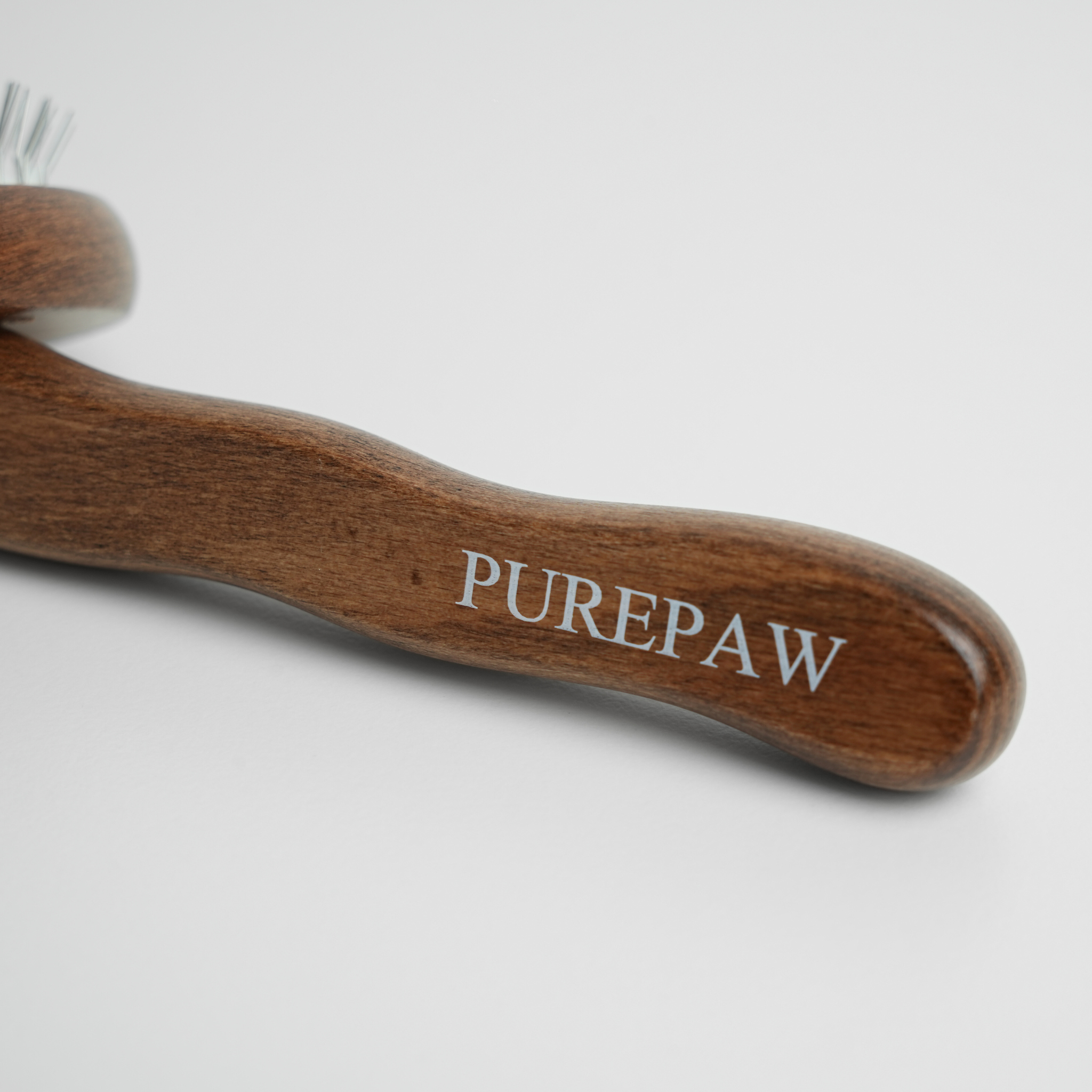 Wooden dog brush with 'PUREPAW' branding on a white background